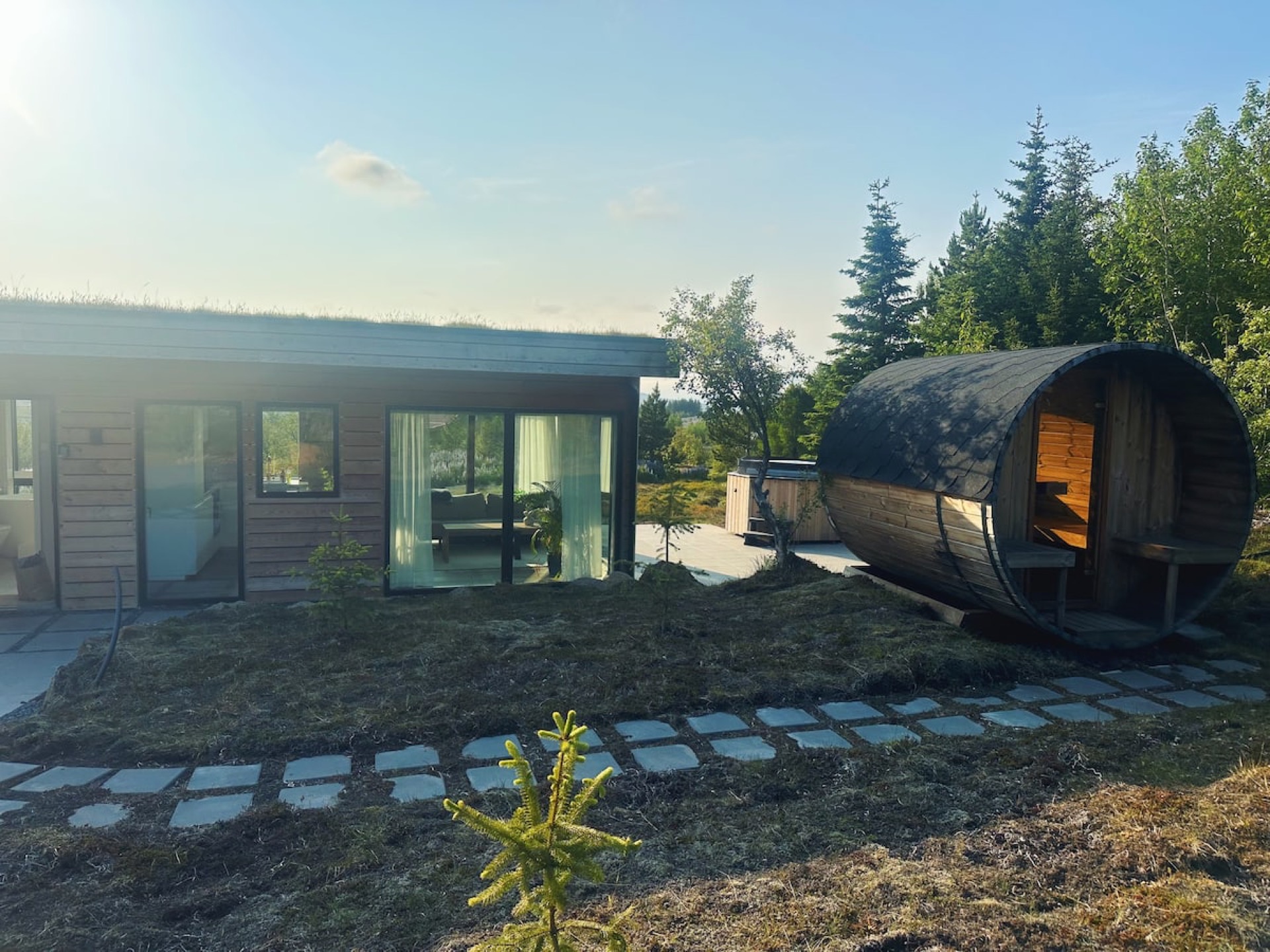 The house and its barrel sauna in summer, stepping stones laid between them