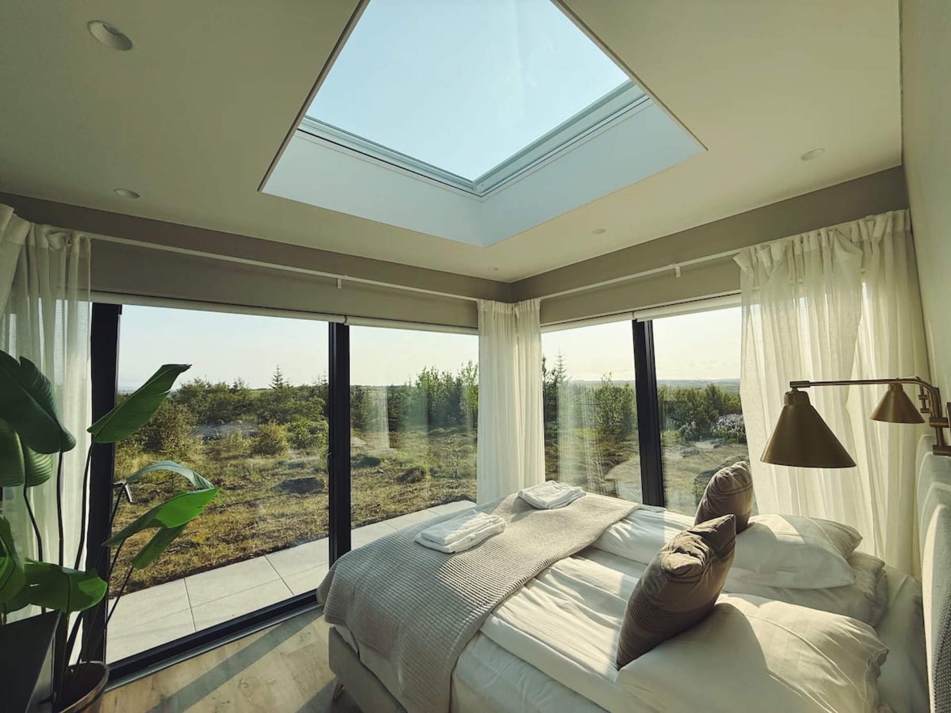 The square skylight set directly over the bed, glass walls opening onto birch scrub