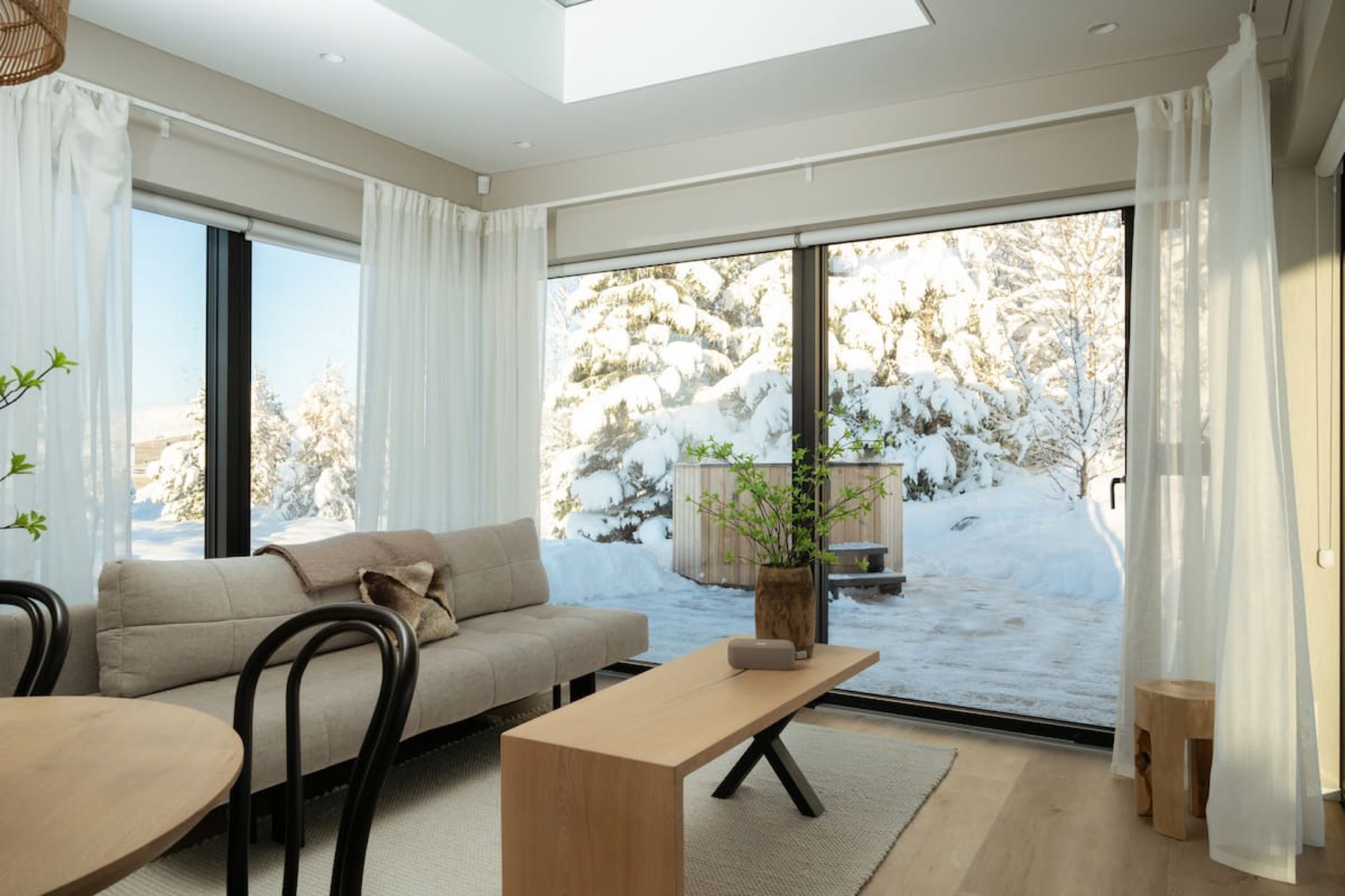 The sitting area, a low sofa facing the glass wall with snow on the heath beyond