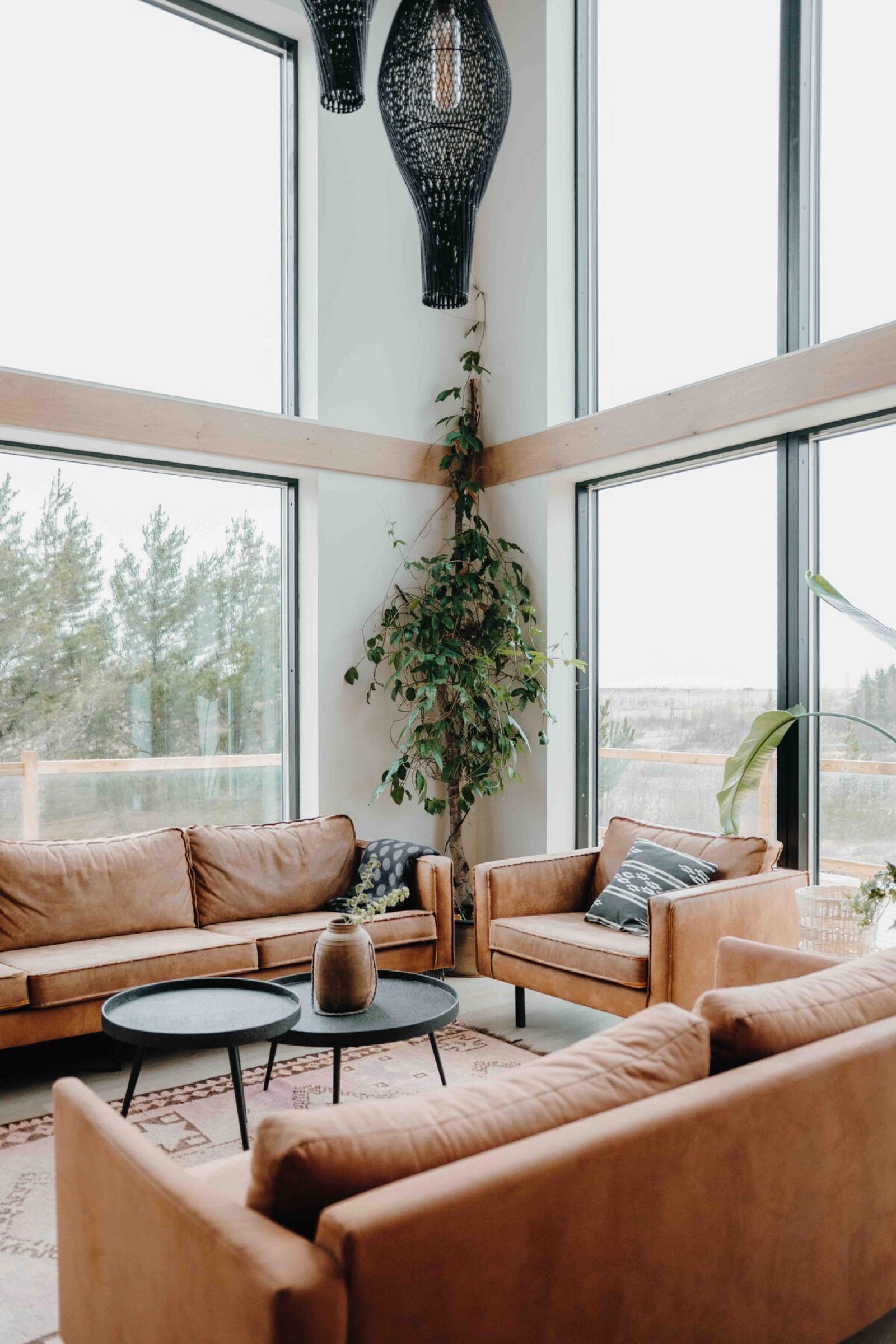 The living room from the floor, two storeys of glass on the corner and woven pendants hanging down into it