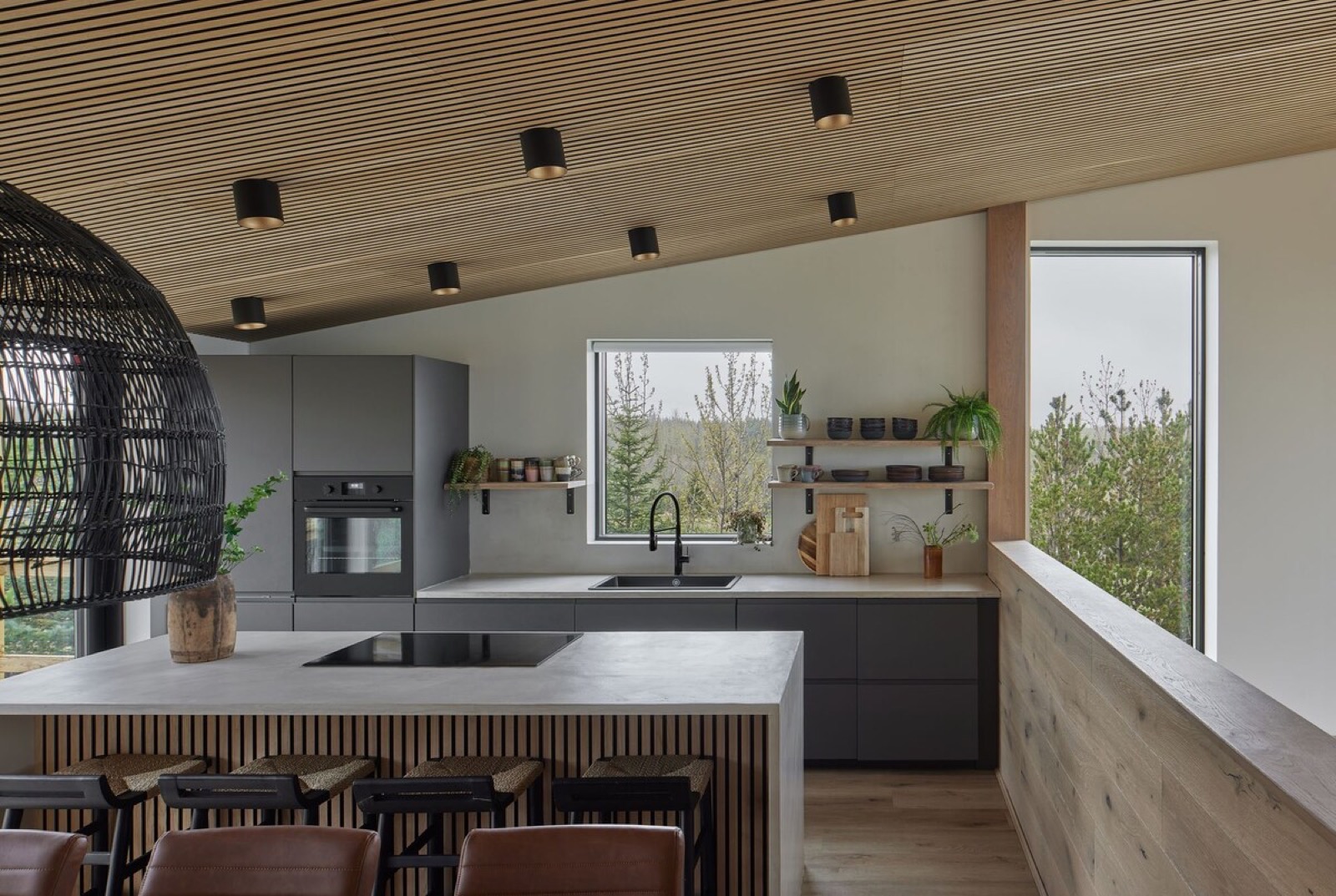 The kitchen island and slatted timber ceiling, woodland through the window