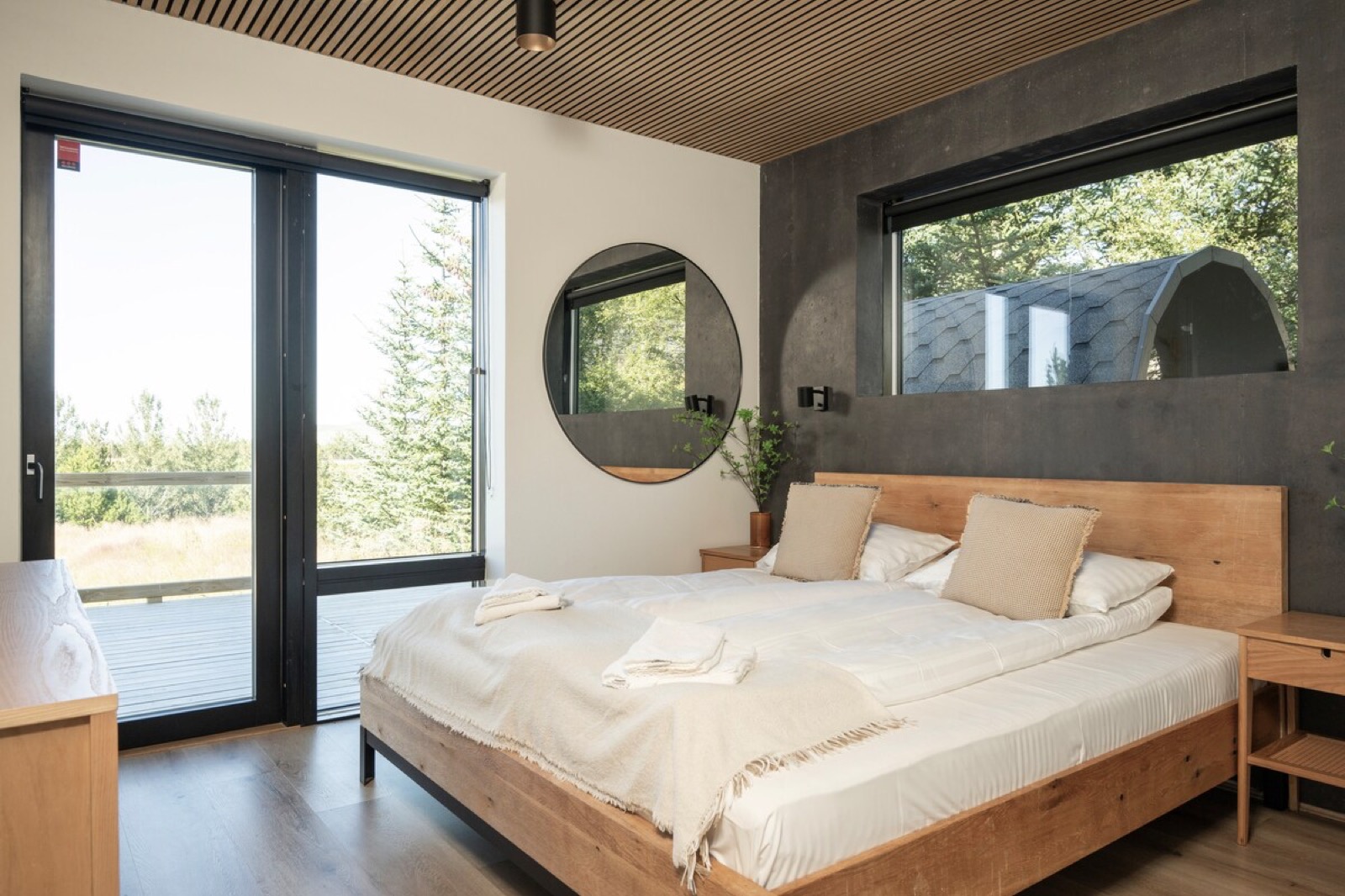 A double bedroom with a full height glazed door onto the deck and a round window beside the bed