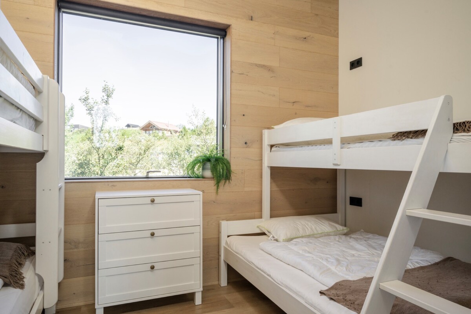 The bunk room, white framed bunks beside a window onto the woodland