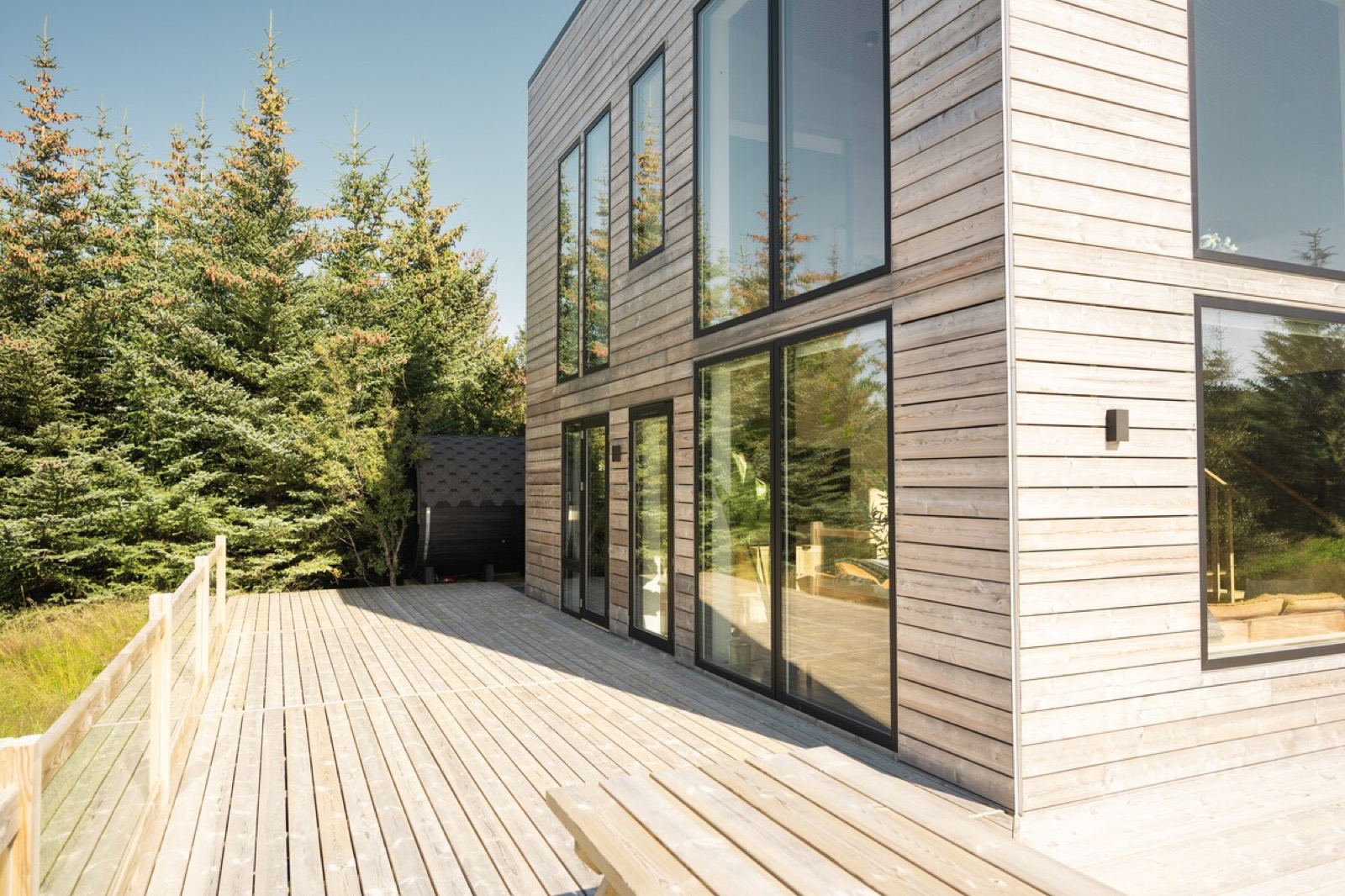 The timber deck running along the fully glazed face of the villa
