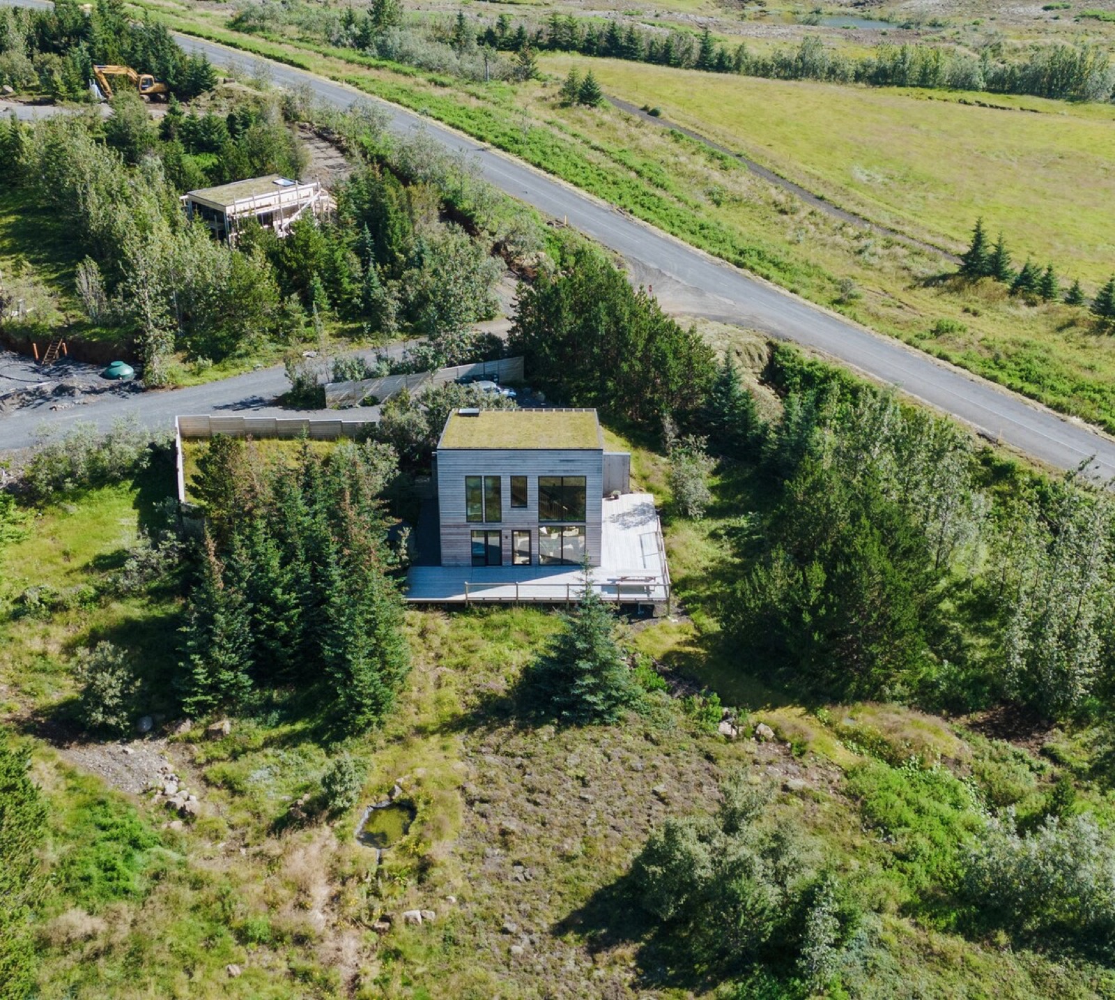 The villa from the air, spruce on three sides and the road running past below