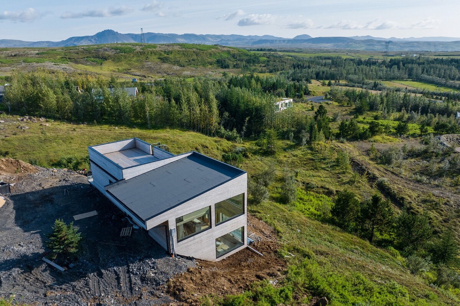 The house standing alone on the green ridge, its glazed end facing out over the valley