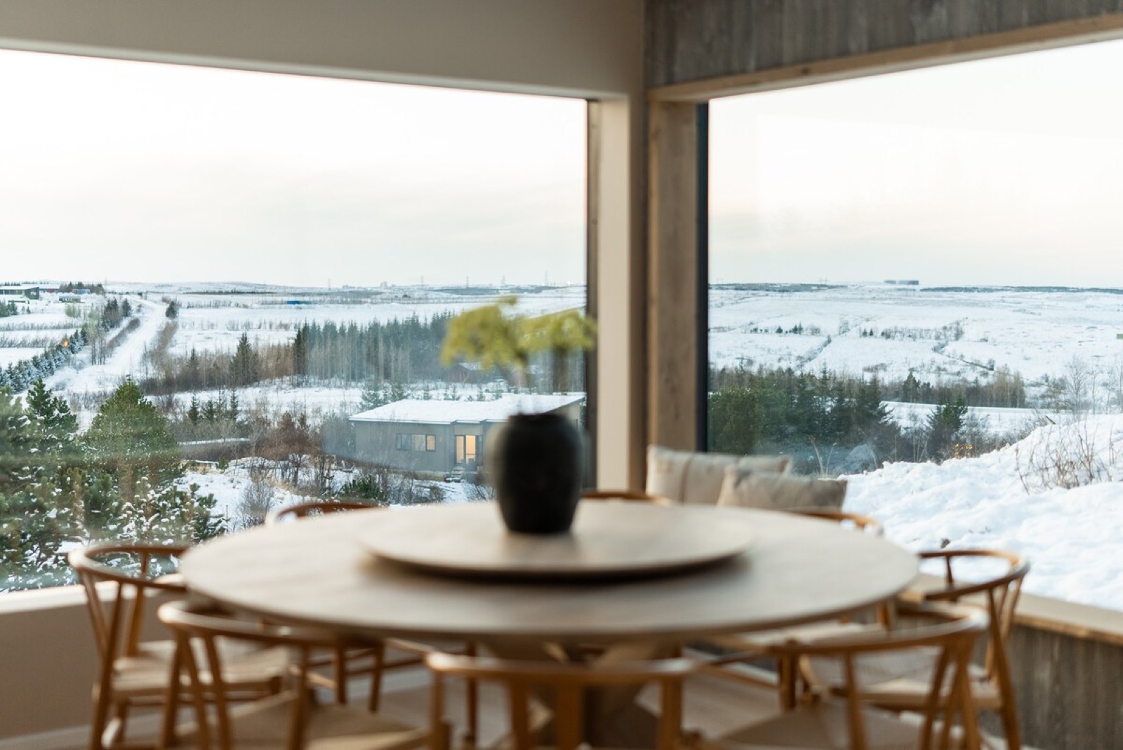 The round dining table and wishbone chairs at the window, snow outside