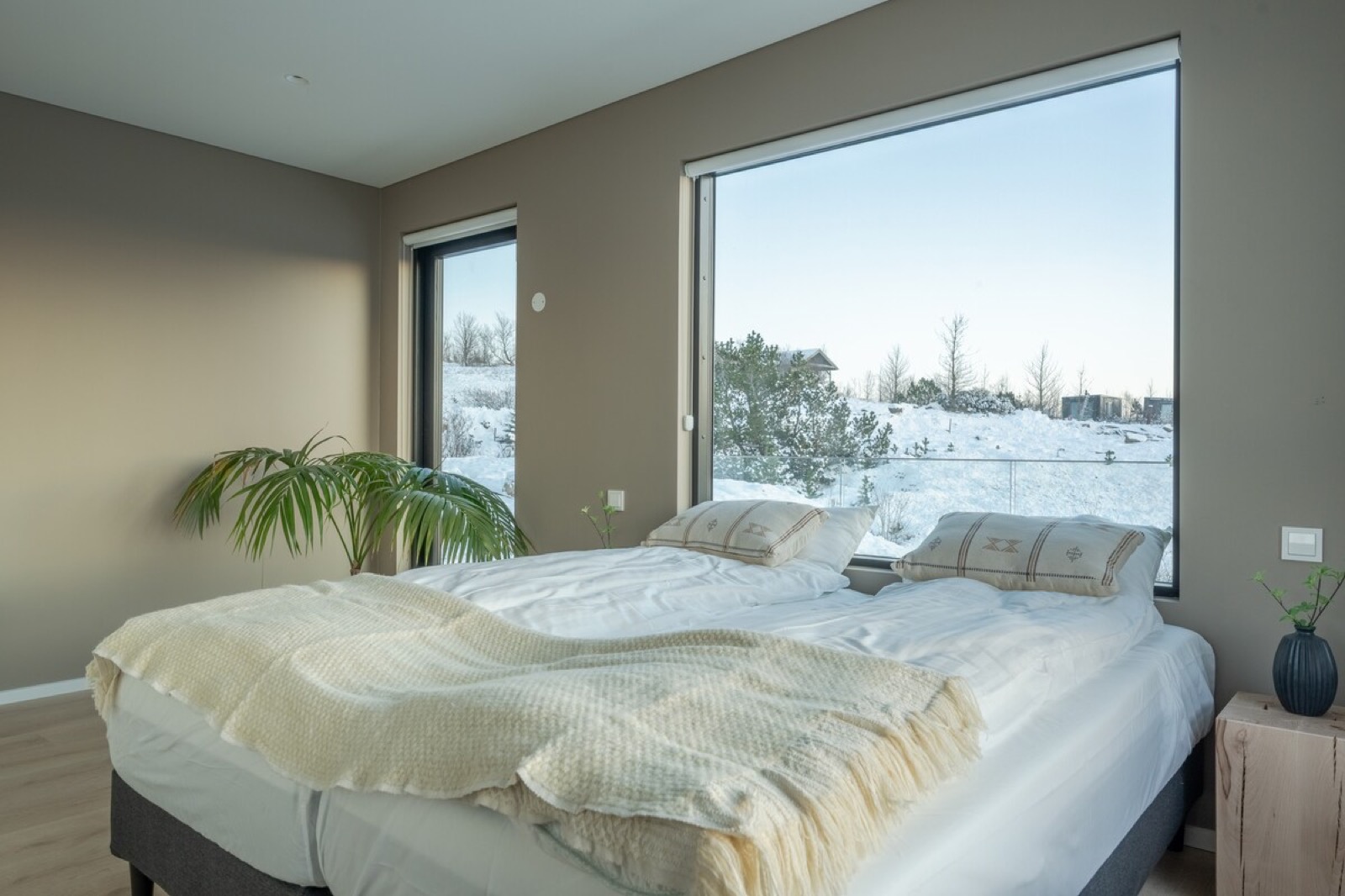 A bedroom with a long horizontal window laid across the snowy lowland
