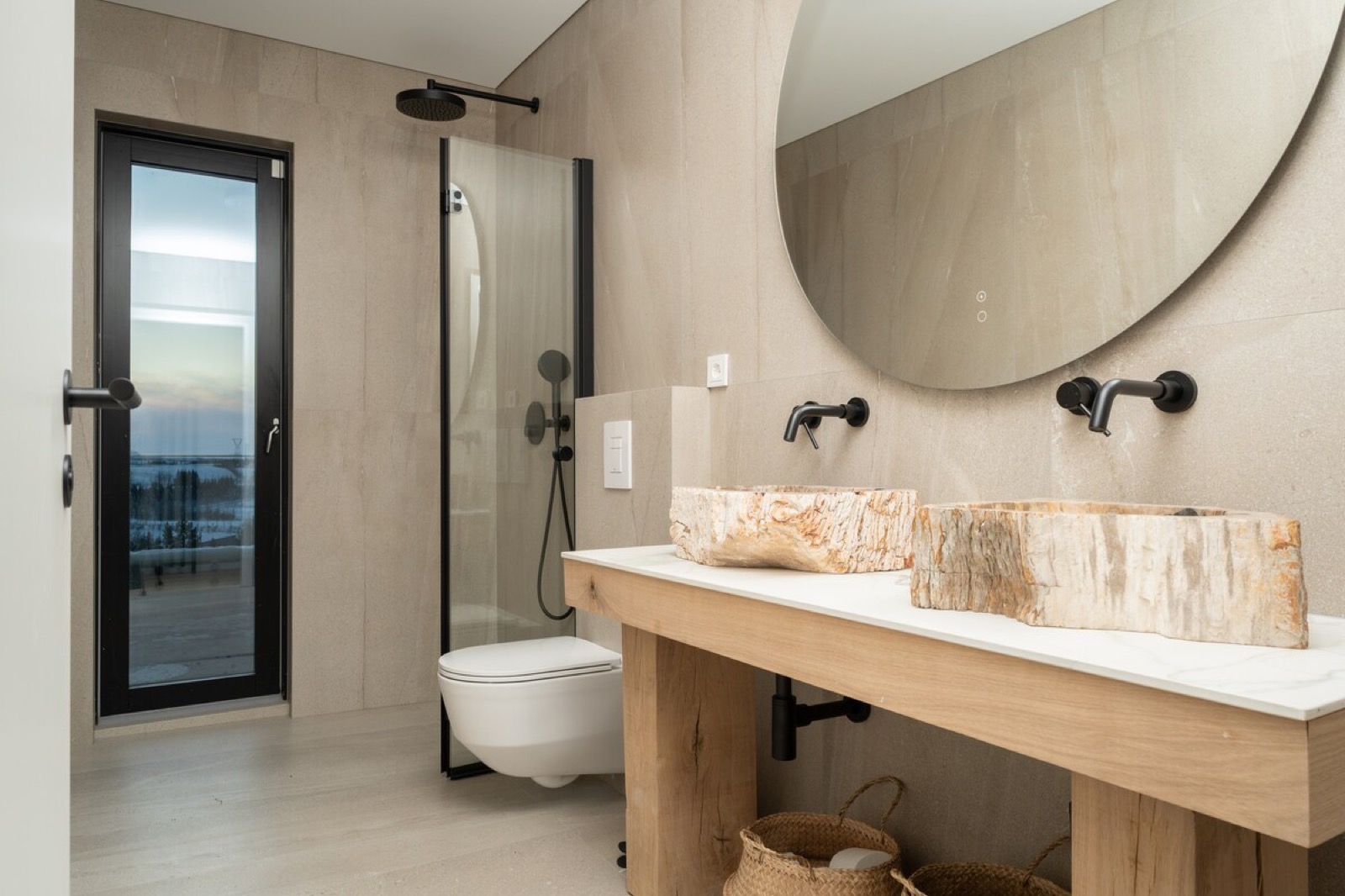 The bathroom, a stone basin set on a timber vanity below a round mirror